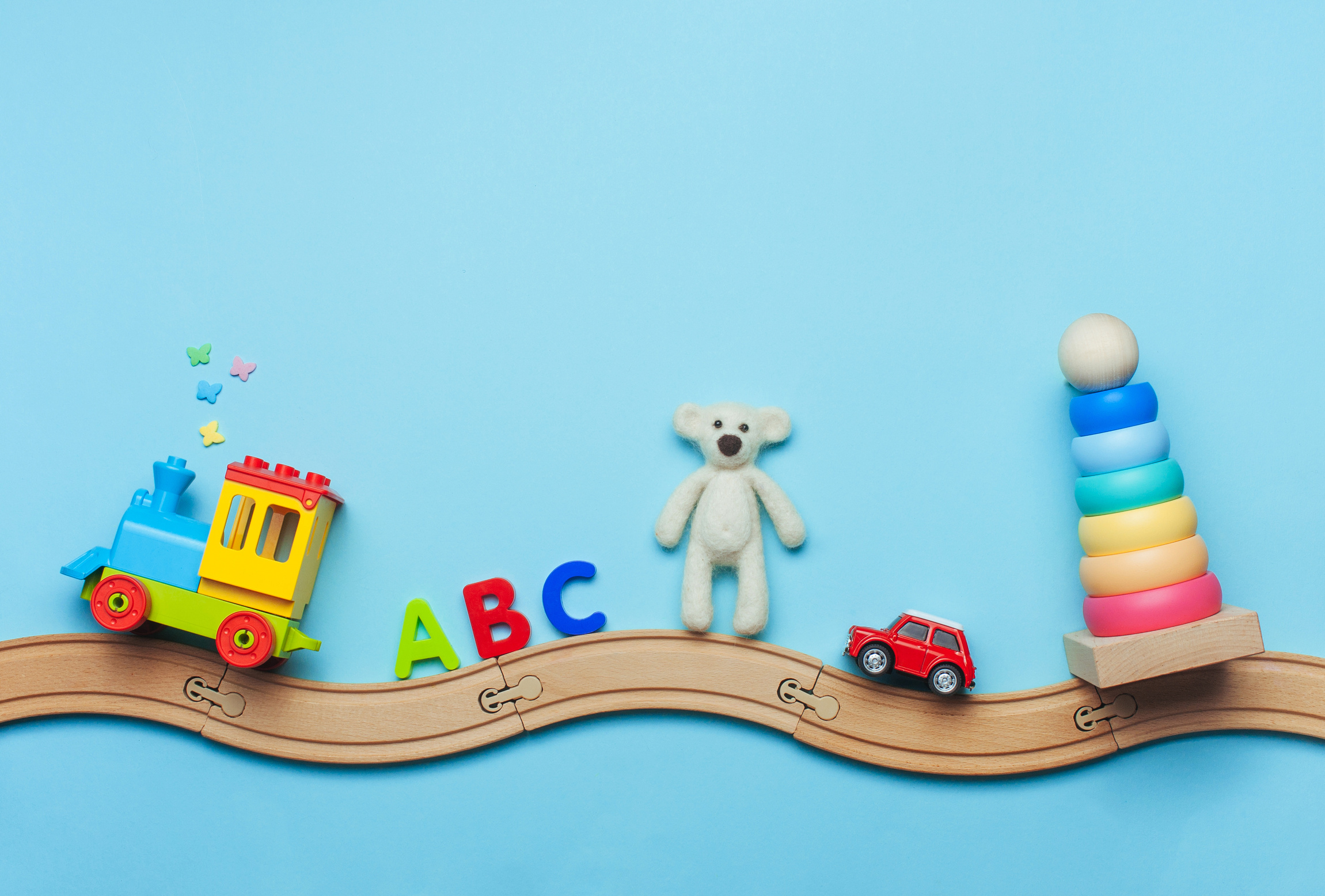 Kids toys on toy wooden railway on blue background